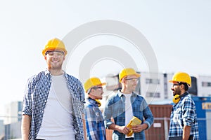 Group of smiling builders in hardhats outdoors