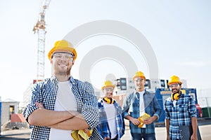 Group of smiling builders in hardhats outdoors