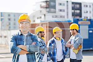 Group of smiling builders in hardhats outdoors