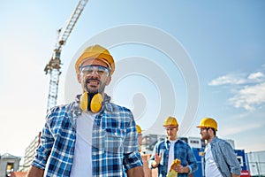 Group of smiling builders in hardhats outdoors