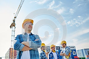 Group of smiling builders in hardhats outdoors