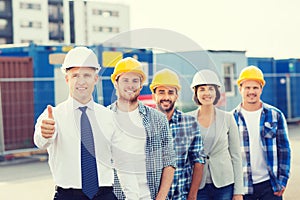 Group of smiling builders in hardhats outdoors