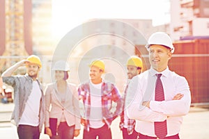 Group of smiling builders in hardhats outdoors