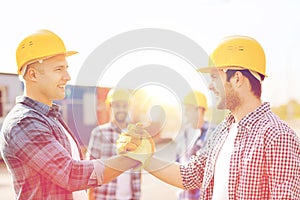 Group of smiling builders in hardhats outdoors