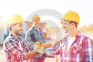 Group of smiling builders in hardhats outdoors