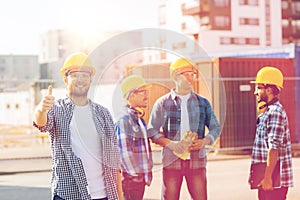 Group of smiling builders in hardhats outdoors