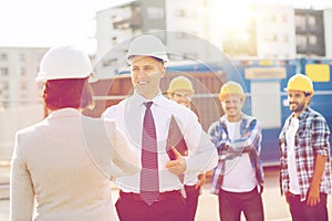 Group of smiling builders in hardhats outdoors