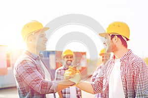 Group of smiling builders in hardhats outdoors