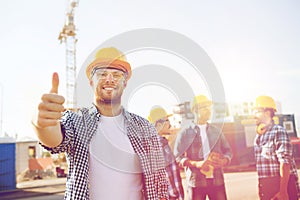 Group of smiling builders in hardhats outdoors