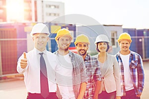 Group of smiling builders in hardhats outdoors