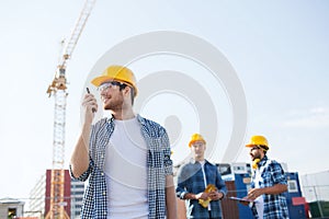 Group of smiling builders in hardhats with radio