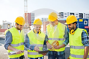 Group of smiling builders with tablet pc outdoors