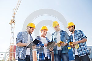 Group of smiling builders with tablet pc outdoors