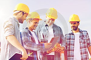 Group of smiling builders with tablet pc outdoors