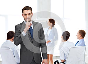 Group of smiling businessmen making hush sign photo