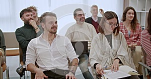 Group of smiling businesspeople applauding during a professional training or seminar in a modern office setting.