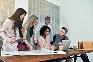 Group of smiling businesspeople working together around an office table