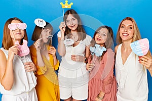 A group of smiling caucasian female models to have gender reveals envent, isolated blue background.