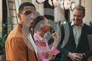 Group of smiling coworkers is talking during break time in office. Corporate unity concept