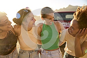 Group Of Smiling Female Friends Standing By Car Having Fun On Road Trip On Vacation