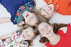 Group of smiling four kids laying on floor. Upper view