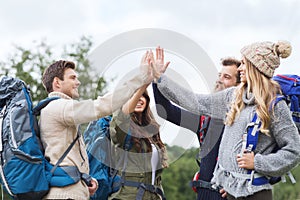 Group of smiling friends with backpacks hiking