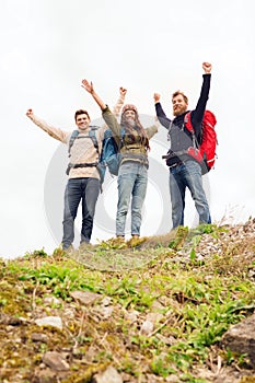 Group of smiling friends with backpacks hiking