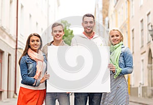 Group of smiling friends with blank white board