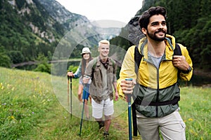 Group of smiling friends hiking with backpacks outdoors. Travel, tourism, hike and people concept.