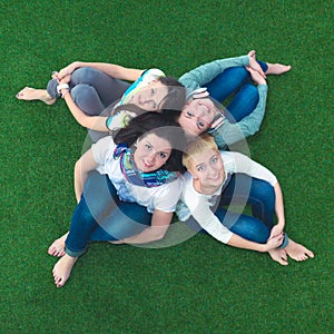 Group of smiling friends lying on grass in circle