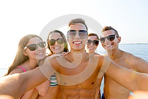 Group of smiling friends making selfie on beach
