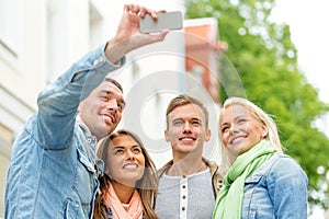 Group of smiling friends making selfie outdoors