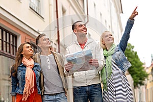 Group of smiling friends with map exploring city