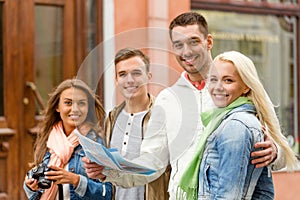 Group of smiling friends with map and photocamera