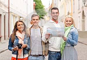 Group of smiling friends with map and photocamera