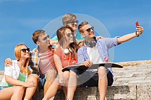Group of smiling friends with smartphone outdoors