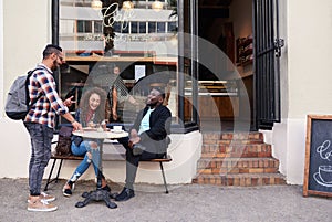 Group of smiling friends talking together at a sidewalk cafe