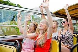 Group of smiling friends traveling by tour bus