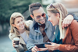 Group of smiling friends using digital tablet