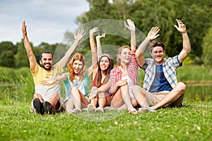 Group of smiling friends waving hands outdoors