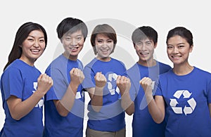 Group of smiling and happy people wearing recycling symbol t-shirts standing in a row with raised fists, studio shot