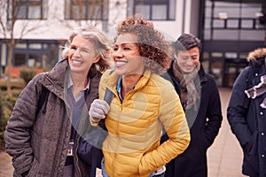 Group Of Smiling Mature Students Walking Outside College Building