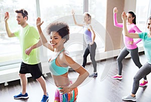 Group of smiling people dancing in gym or studio