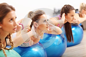 Group of smiling people doing aerobics with balls