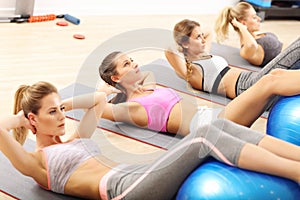 Group of smiling people doing aerobics with balls