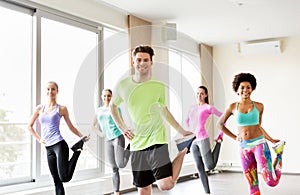 Group of smiling people exercising in gym