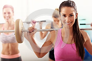Group of smiling people lifting barbells