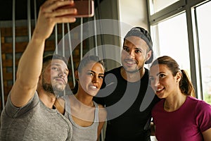 Group of smiling people making self-picture in gym.