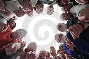 Group of smiling people pointing at the camera