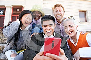 Group of Smiling people using mobile phone outdoors. Cheerful guys and girls friends having fun watching